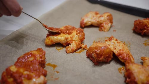 Chicken Wings Being Prepared with Red Sauce