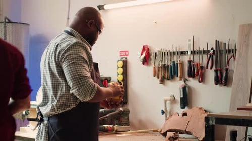 Artisan in Studio Using Sandpaper for Smoothing Wooden Surface