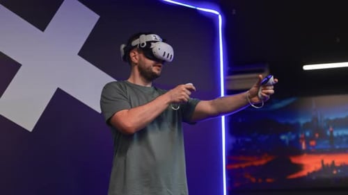 Man Interacting in Virtual Reality Using VR Headset and Joysticks at a VR Lounge Physically Moving