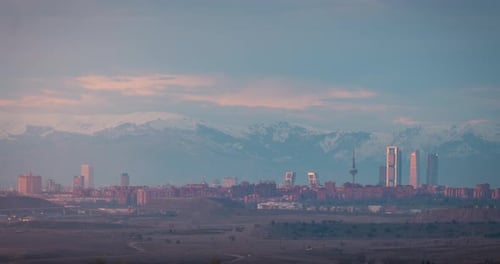 Madrid downtown skyline sunset time lapse day to night snowy Gadarrama mountains as background.