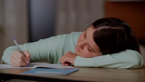 The Girl Lies on the Desk and Tries to Finish Her Homework A Tired Brunette Girl Lay Down on the