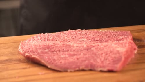 Tenderizing Raw Beef Steak on Wooden Cutting Board