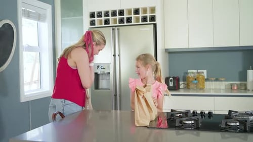 Madre con la cabeza roja y su hija con la parte superior rosa clasificando la comida en la isla, mamá entregando bolsas de malla, llenando bolsas de malla