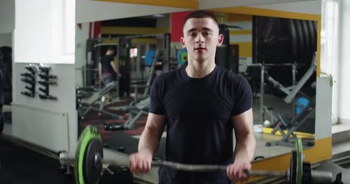 Closeup View of Sporty Man Performing Barbell Curls to Gain Lean Biceps