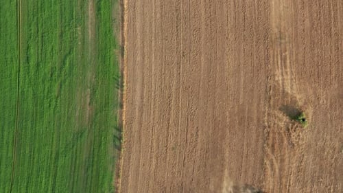 Aerial - Industrial Farm Tractor Tilling & Ploughing Land in Pattern for Harvest