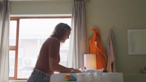 Video of happy caucasian mother changing newborn baby