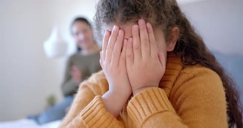 Mère nerveuse réprimandant sa fille au lit dans une chambre ensoleillée