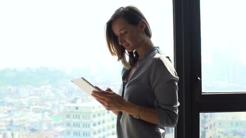 Woman Using Tablet Device by Office Window