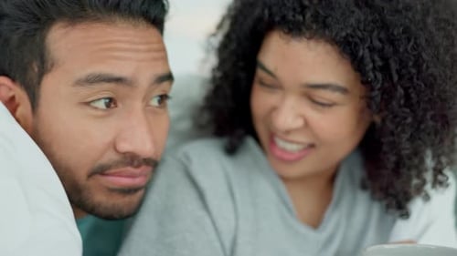 Happy Couple Smiling Under Blanket in Bed