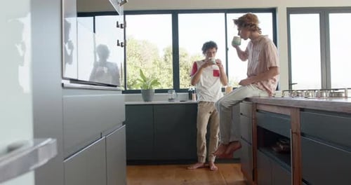 Two Young Adults Drinking Coffee in Modern Kitchen