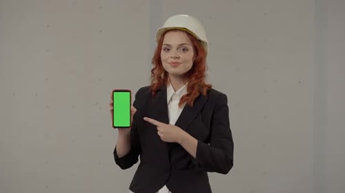 A Female Architect is Holding Smartphone Screen Facing Forward Pointing at Its Green Screen Portrait