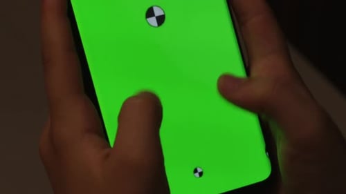 Hands holding smartphone with green screen
