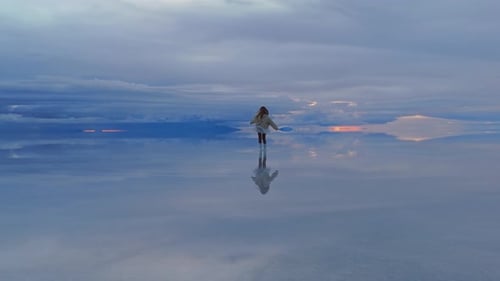 Una mujer corre por la superficie reflectante del Salar de Uyuni de Bolivia al amanecer creando un