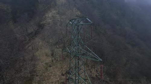 High Voltage Pylon and Power Lines with Misty Mountain Backdrop, Aerial View