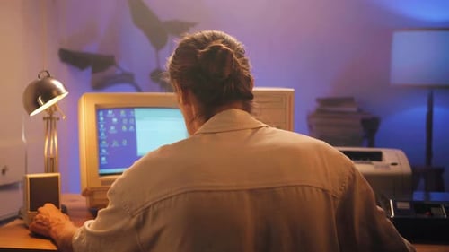 Hombre trabajando y jugando en una computadora retro, ingeniero de TI con una computadora antigua en casa usando una vieja