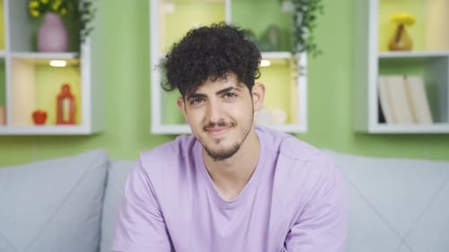 Junger Mann schaut in die Kamera und lacht. Positiver Ausdruck.