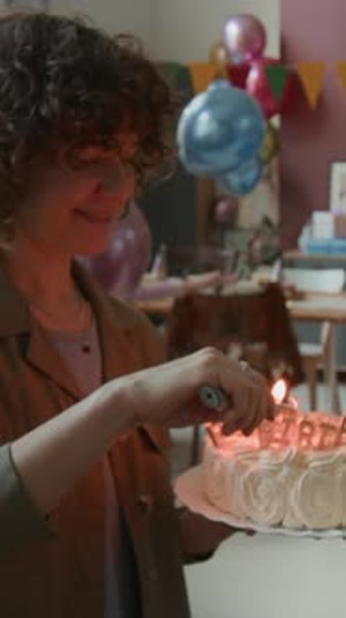 Woman Lighting Up Candles on Birthday Cake While Children Playing with Balloons