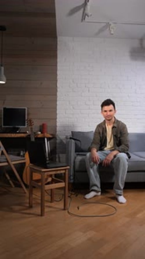 Vertical Video Musician Creating and Producing Music in a Home Recording Studio Sitting on a Sofa