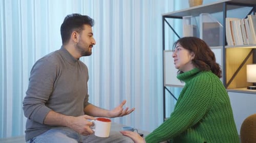 Man and Woman Talking and Gesturing Indoors