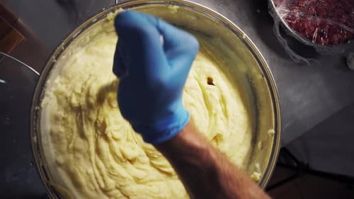 Un chef en cuisine mélange de la purée de pommes de terre dans une casserole
