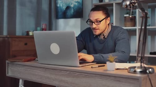 A Focused Professional Engaged in Work on Laptop in a Contemporary and Modern Home Office Space
