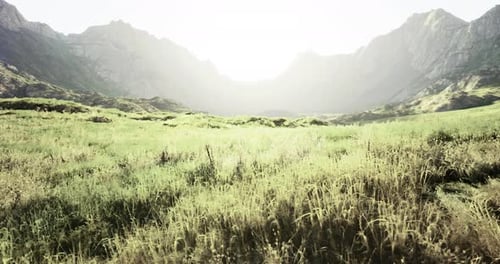 Majestic Mountain Landscape with Lush Green Fields Under Bright Sunlight