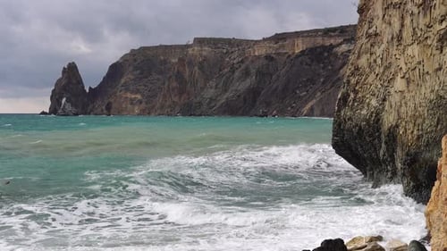 Mer orageuse au coucher du soleil Les vagues s'écrasent sur la roche de basalte volcanique éclairée par la chaleur du soleil