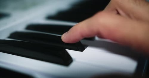 Young professional male musician playing chords on the piano with two hands inside his home studio.