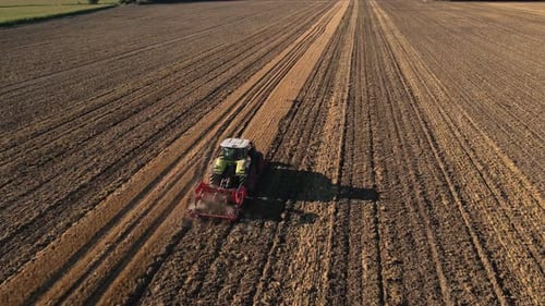 Tractor working on agricultural field, plowed farmland