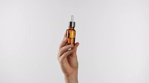 Hand Holding Amber Glass Dropper Bottle