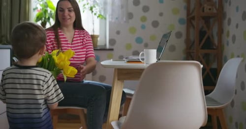 Boy Gives Flowers to Loving Woman in Home
