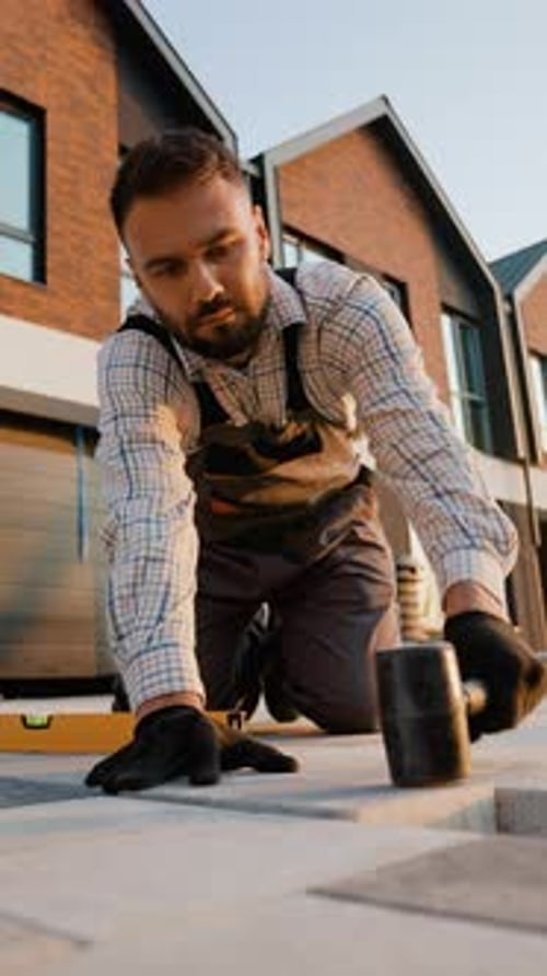 Construction Worker Laying Paving Slabs with Mallet and Level