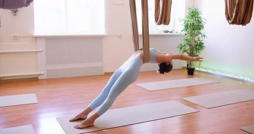 Woman Performing Aerial Yoga Exercise in Bright Studio