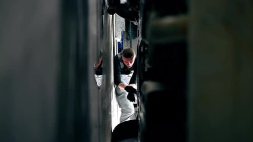 Vertical Video a Lying Auto Mechanic at a Service Station Repairing Part of Wheel Panel