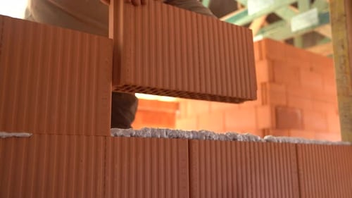 Trabajador coloca ladrillos cerámicos huecos para construir un muro en el sitio de construcción de una casa