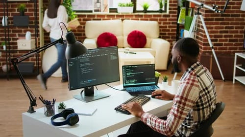 Young Man Seen Programming Software Code on His Laptop in a Sleek Home Office