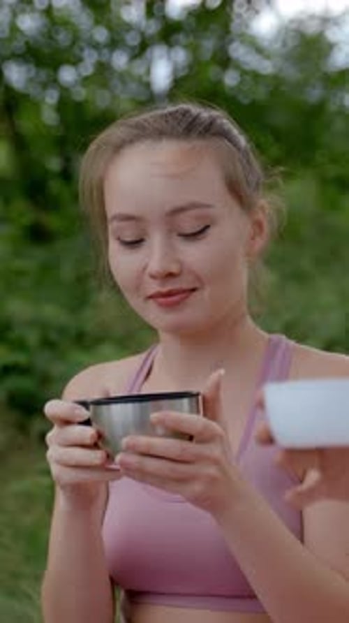 Vertical of Couple of Tourists Drinks Hot Beverage Against Trees
