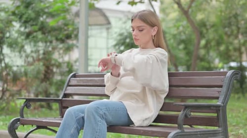 Woman Checks Smartwatch While Sitting on Park Bench