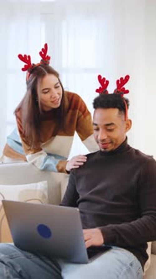 Couple Enjoys Quality Time at Home During the Christmas Season Wearing Reindeer Headbands and