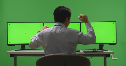 Happy Man Celebrating And Dancing While Working With Mock Up Multiple Monitor In Green Screen Studio