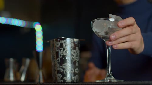 Close Up Bartender Throwing Away Ice Cubes From a Small Cocktail Glass Media Cooling a Glass for