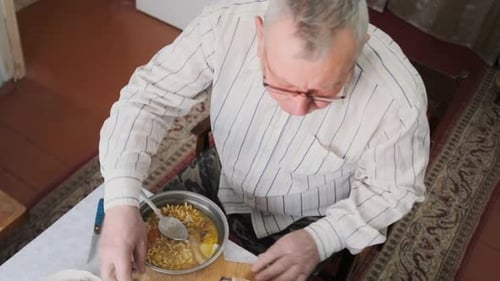 Senior Man Eating Soup at Table Indoors