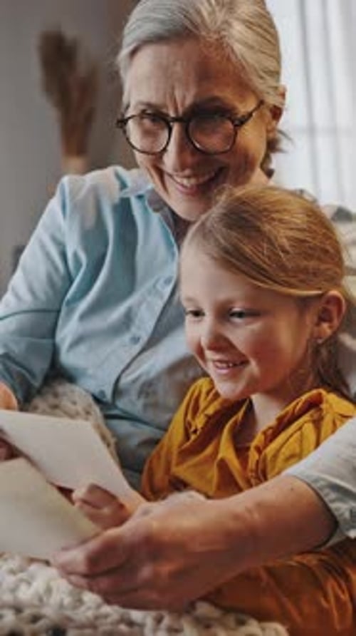 Grandmother and Granddaughter Looking at Photos Together Indoors