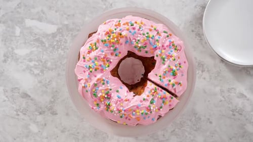 Zeitraffer Flat Lay Funfettti Bundt-Kuchen in Scheiben mit rosafarbenem Buttercreme-Zuckerguss auf der Oberseite und