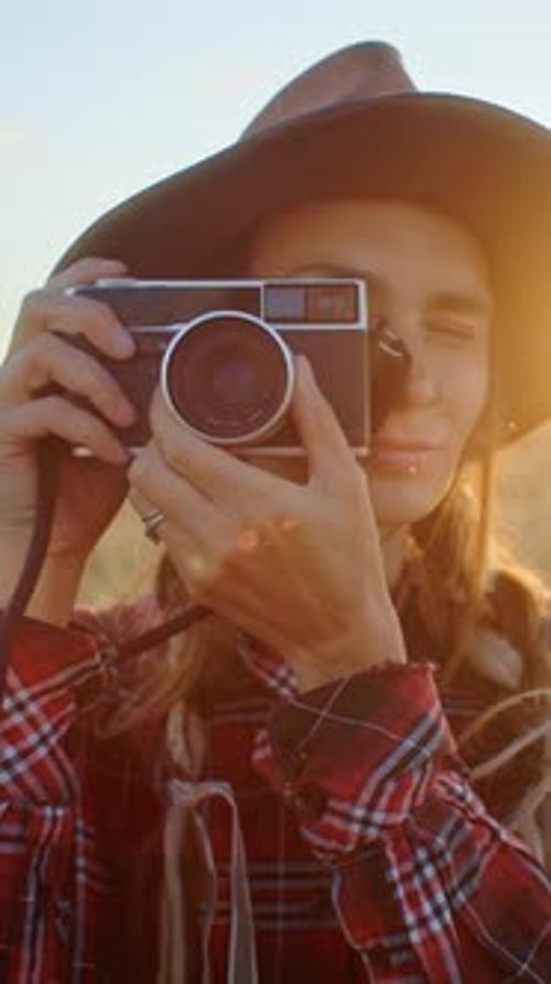 Photographer Taking Pictures with Vintage Camera in a Field at Sunset