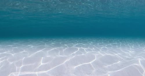 Blaues Meer unter Wasser mit weißem sandigem Meeresboden und Wellenwasserhintergrund