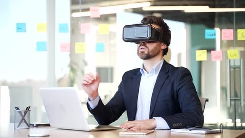 Businessman in formal suit works using VR glasses in virtual reality simulator sitting at workplace