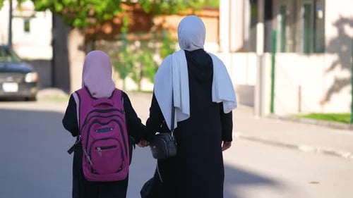 A woman takes her little daughter to school in the morning.