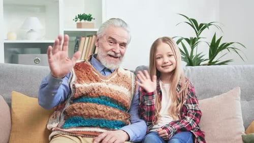 Grandfather and Granddaughter Waving From Sofa