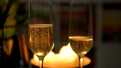 Glasses Half-filled With Bubbly Champagne On Candlelit Dinner Table. close up